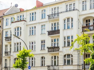 Wohngebäude in Berlin mit weißen Fassaden und Balkonen, umgeben von Bäumen