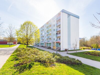 Modernes Wohngebäude mit gepflegten Grünflächen und Fußweg bei sonnigem Wetter