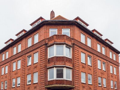 Eckgebäude mit markanter Backsteinfassade und zahlreichen Fenstern an einem bewölkten Tag