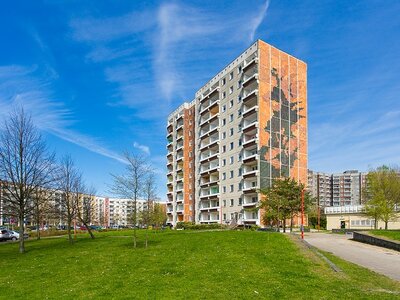 Mehrstöckiges Wohngebäude mit künstlerischer Fassadengestaltung, umgeben von Grünflächen bei klarem Himmel