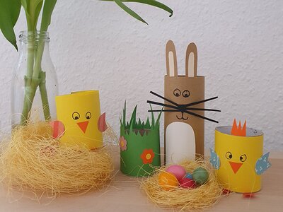 Osterdekoration mit selbstgebastelten Küken, Osterhase und bunten Eiern auf einem Tisch