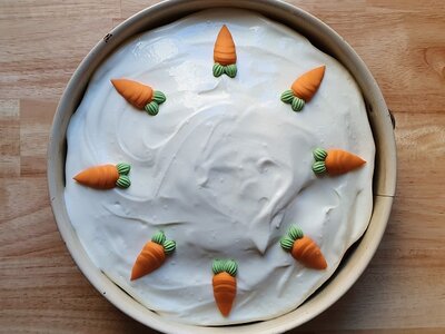 Rüblikuchen mit weißem Zuckerguss und Marzipankarotten als Dekoration